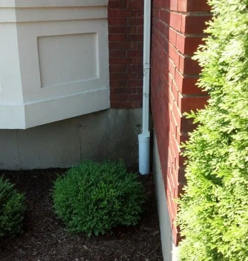 Gutter downpipe drain installed along brick siding