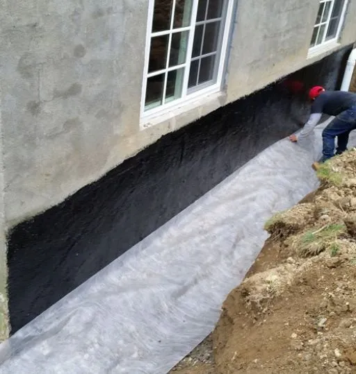 Worker installing French drain system outside home