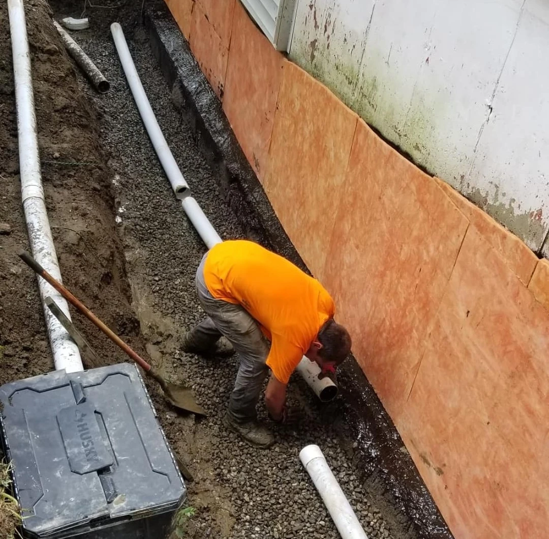 Worker installing underground curtain drain